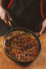 The cook prepares meat with vegetables and onion in a bowl . Oriental cuisine