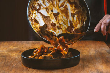Chef cooks Chinese food in a pan, stirring with a wooden spoon