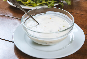yogurt soup with herbs in a plate on a wooden table.spas