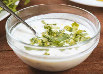 yogurt soup with herbs in a plate on a wooden table.spas