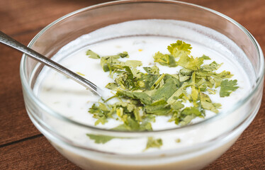 yogurt soup with herbs in a plate on a wooden table.spas