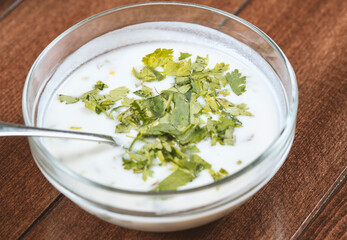 yogurt soup with herbs in a plate on a wooden table.spas