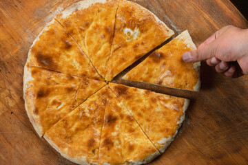 Persons take pieces of baked homemade cheese pie on wooden background. Bulgarian banitsa, Georgian...