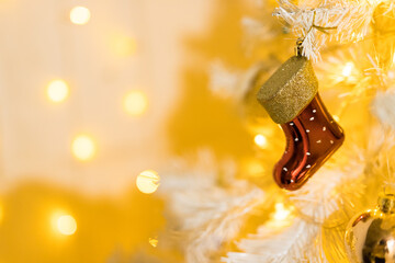 Close up of holidays location with red gold sock toy and garlands on white yellow Christmas tree