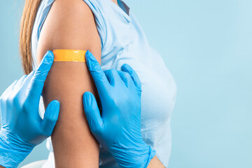 Doctor hands putting a band-aid at female arm after injection of a corona virus vaccine