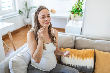 Pregnant woman taking a Self-swabbing home tests for COVID-19 at home with Antigen kit. Introducing nasal stick to check the infection of Coronavirus. Quarantine, pandemic.