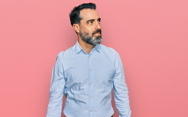 Middle aged man with beard wearing business shirt looking away to side with smile on face, natural expression. laughing confident.