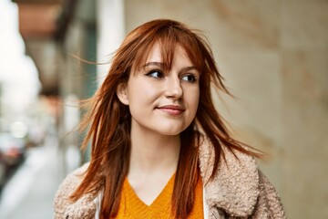 Young redhead girl smiling happy standing at the city.