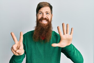 Redhead man with long beard wearing casual clothes showing and pointing up with fingers number...