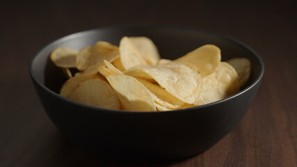 potato chips in black bowl on wood table