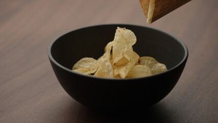 potato chips in black bowl on wood table