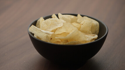 potato chips in black bowl on wood table