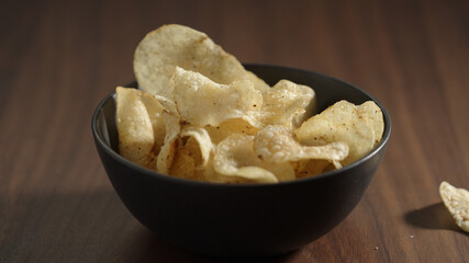 potato chips with black pepper in black bowl on wood table