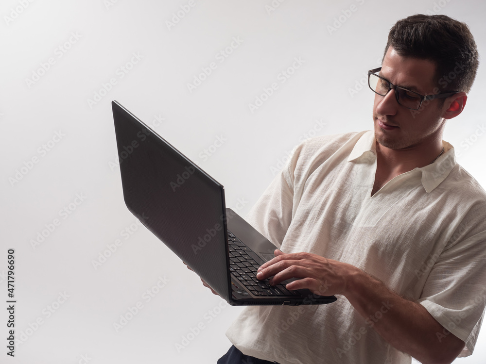 Poster computer master with a laptop in his hands. portrait of computer master on light background. he is t
