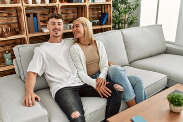 Young caucasian couple smiling happy and hugging sitting on the sofa at home.