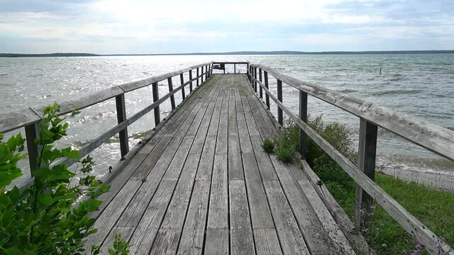 Old Weather Worn Dock--stretching out into a lake; front view of dock, walk out on dock--overcast day with sun breaking through 