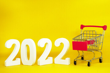 2022 number with shopping cart on yellow background - End of year 2021 and Happy new year 2022...