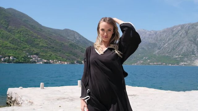 Portrait of gorgeous girl looking to camera. tall sexy brunette woman. woman in blue dress blowing her hair in the wind. mysterious beautiful woman outdoors