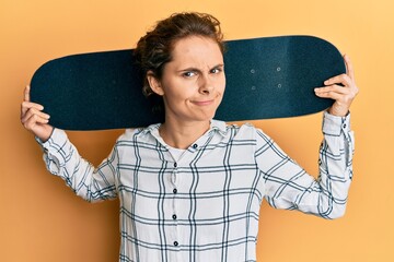 Young brunette woman holding skate skeptic and nervous, frowning upset because of problem. negative...