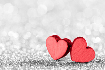 Two red hearts on glittering background