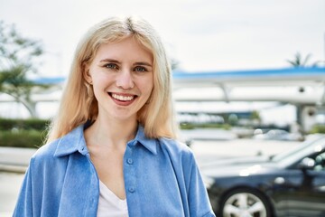 Beautiful blonde young woman smiling happy outdoors on a sunny day