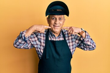 Fototapeta premium Handsome senior man with grey hair wearing welding protection mask smiling cheerful showing and pointing with fingers teeth and mouth. dental health concept.