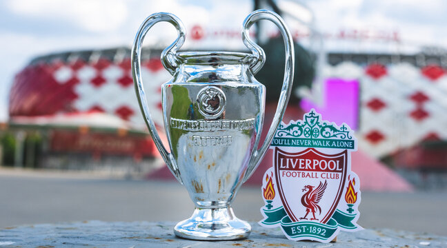 June 14, 2021 Liverpool, UK. Liverpool F.C. Football Club emblem and the UEFA Champions League Cup against the backdrop of a modern stadium.