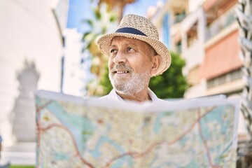 Senior man smiling confident wearing summer hat holding map at street