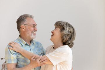 Cheerful old married couple hugging, dancing, laughing against white wall background. Happy grey haired husband and wife celebrating anniversary, having fun. Long time marriage, elderly age concept