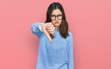 Young beautiful woman wearing casual clothes and glasses looking unhappy and angry showing rejection and negative with thumbs down gesture. bad expression.