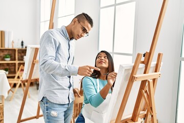 Obraz premium Young latin painter couple with serious expression painting at art studio