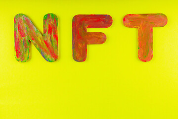 Non fungible token. NFT acronym of multicolored letters on yellow background. Crypto Art concept....