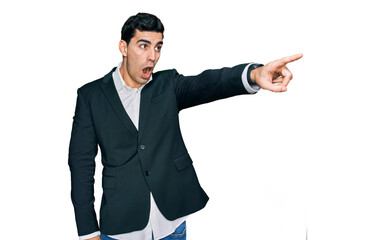Handsome hispanic man wearing business clothes pointing with finger surprised ahead, open mouth amazed expression, something on the front