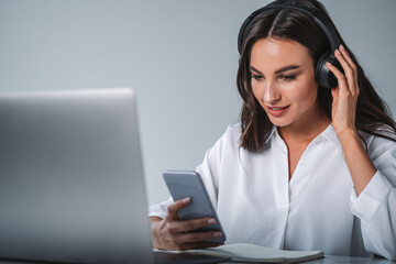 Businesswoman with smartphone in hands wearing headphones, desk