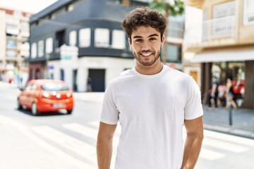 Young hispanic man smiling happy standing at the city.