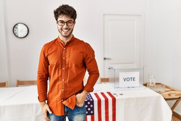 Hispanic man standing by election room winking looking at the camera with sexy expression, cheerful...