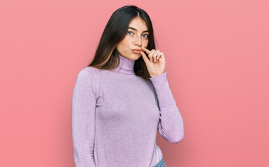 Young beautiful teen girl wearing turtleneck sweater mouth and lips shut as zip with fingers....
