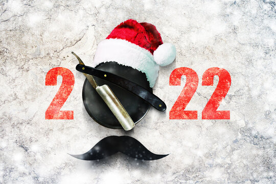 Razor on a plate for foam with a Santa Claus hat on a gray background. Numbers 2022. Greeting card Happy New Year and Merry Christmas for a hairdresser and barbershop.