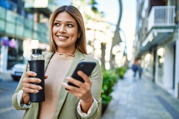 Young latin woman smiling confident using smartphone at street