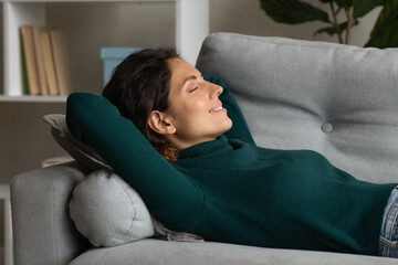 Nap time. Serene millennial hispanic female dreaming sleeping on cozy couch at living room lying on...