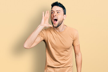 Hispanic man with beard wearing casual t shirt shouting and screaming loud to side with hand on mouth. communication concept.