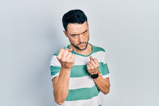 Young hispanic man wearing casual clothes ready to fight with fist defense gesture, angry and upset face, afraid of problem