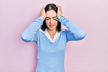 Beautiful woman with blue eyes standing over pink background suffering from headache desperate and stressed because pain and migraine. hands on head.