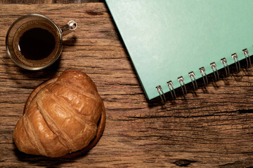 Breakfast food croissant in plate and coffee on wood table.