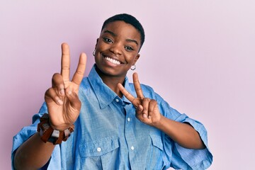 Young african american woman wearing casual clothes smiling looking to the camera showing fingers...