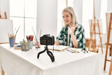 Young artist student girl dmiling happy painting. Sitting on desk recording art class at art studio.