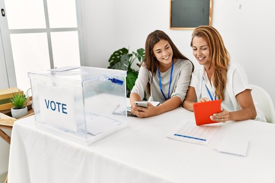 Mother and daughter smiling confident using touchpad working at electoral college