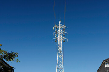 Obraz premium 高圧送電線、青空を背景に高くそびえる鉄塔