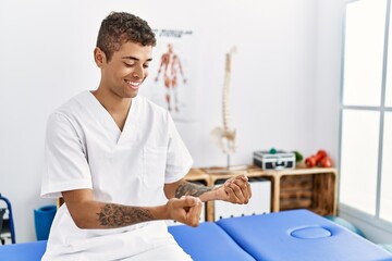 Young hispanic man working as physiotherapist holding small balls at physiotherapy room