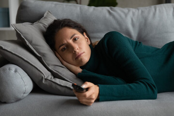 After hard working day. Exhausted millennial latin woman lying on soft couch watching evening...